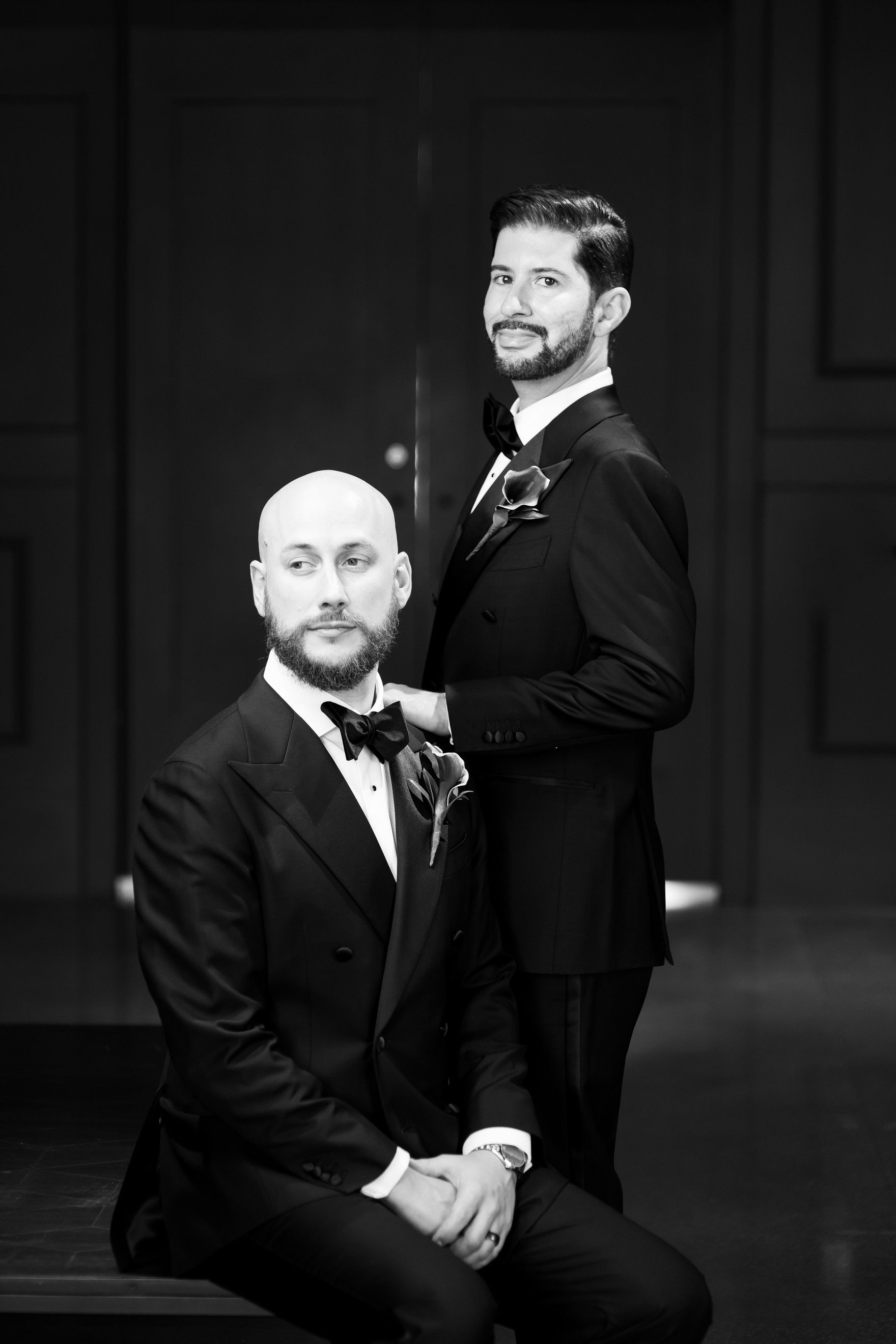 Michael and Kevin in a black-and-white formal wedding portrait, one seated and one standing
