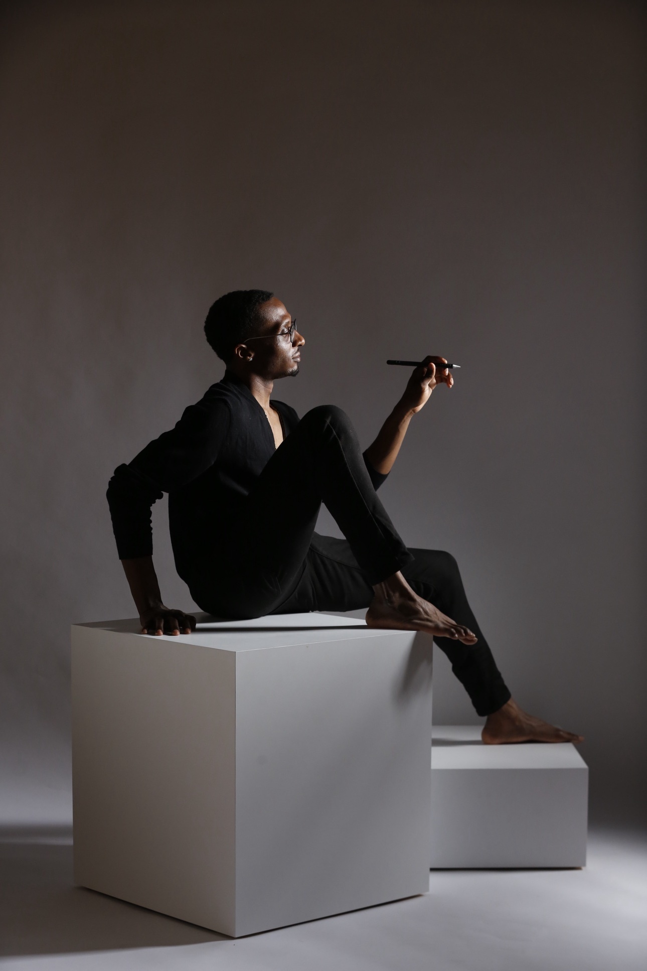 Creative professional seated on white sculptural cubes holding a feather
