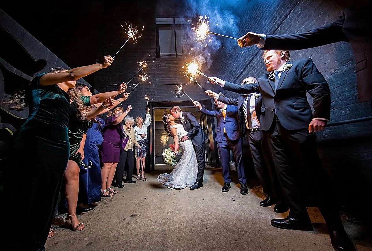 Newlyweds kissing during a sparkling nighttime wedding exit
